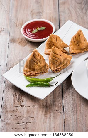 Samosa snack with tomato ketchup and hot tea, Fresh samosas with ketchup and hot chai ready for breakfast
