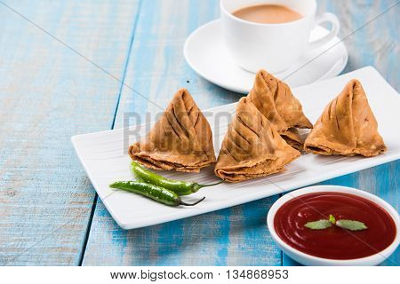 Samosa snack with tomato ketchup and hot tea, Fresh samosas with ketchup and hot chai ready for breakfast