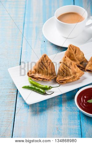 Samosa snack with tomato ketchup and hot tea, Fresh samosas with ketchup and hot chai ready for breakfast
