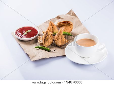 Samosa snack with tomato ketchup and hot tea, Fresh samosas with ketchup and hot chai ready for breakfast