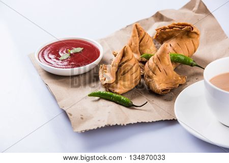 Samosa snack with tomato ketchup and hot tea, Fresh samosas with ketchup and hot chai ready for breakfast