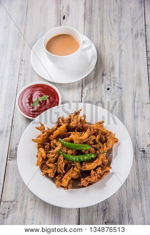 Crispy onion bhaji or kanda bhaji or fried onion pakore or pakode, delicious street food, favourite indian snack in monsoon served with hot tea