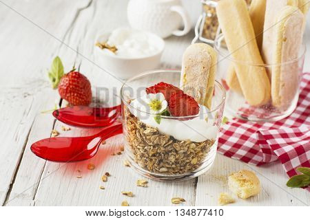 The concept of a healthy breakfast. Crispy homemade granola with nuts and berries with fresh strawberries in a glass portioned cups on a white background are served for breakfast. selective focus