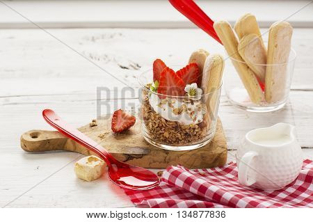 The concept of a healthy breakfast. Crispy homemade granola with nuts and berries with fresh strawberries in a glass portioned cups on a white background are served for breakfast. selective focus