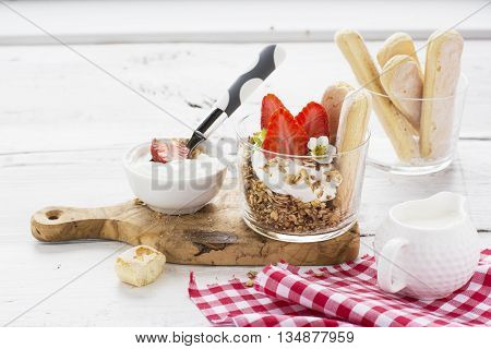 The concept of a healthy breakfast. Crispy homemade granola with nuts and berries with fresh strawberries in a glass portioned cups on a white background are served for breakfast. selective focus
