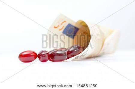 Krill oil capsulesspill out from euro banknote