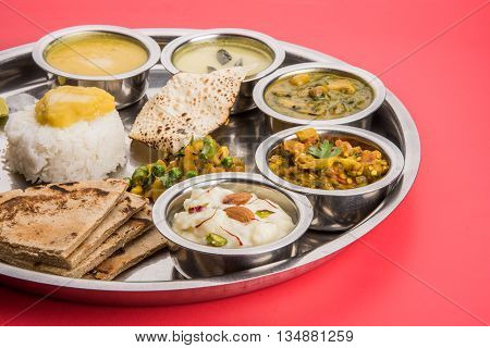 typical maharashtrian food served in a steal plate, marathi food includes kadhi and shrikhand, plain dal, spinach curry, aalu mutter, plain rice, papad, bhakri or bhakar or roti and variety of salad