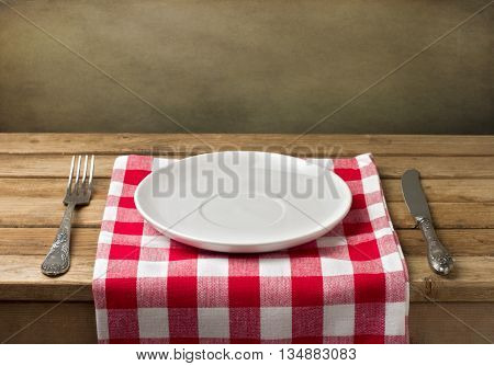 Empty plate on wooden table over grunge background