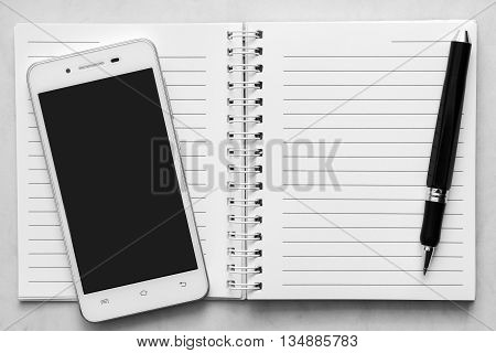 notebook and black color pen and phone or tablet