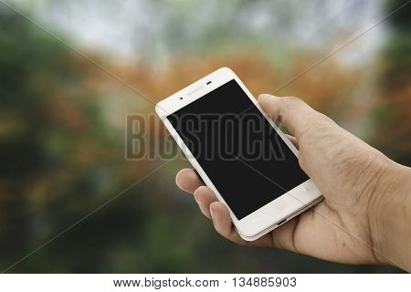 Hand holding mockup smartphone with nature background