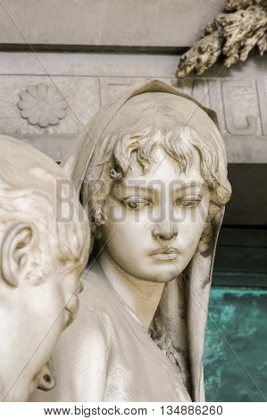 Statue of a grieving girl on monumental cemetery of Staglieno in Genoa.