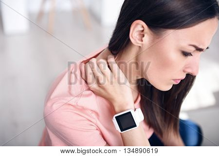 Pleasant sick woman holding her hand on the neck and writhing under pain