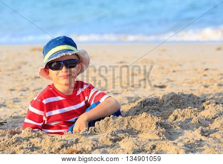 happy cute little boy play with sand on beach