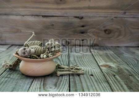 Skull skeleton in clay pot on old wood background