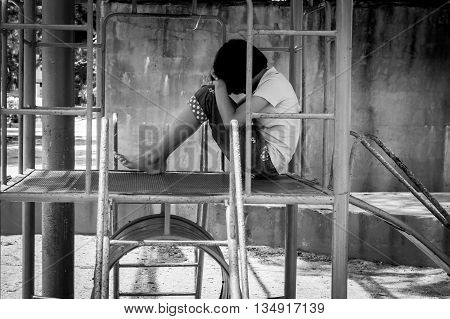 Girl pauper sitting alone at playgroundblack and white tone
