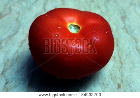 Fresh tomato with water droplets on a marble table