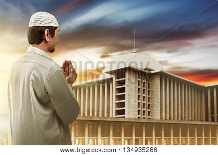 Young Muslim Man Praying Looking To Mosque