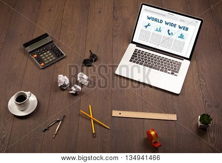 Laptop computer on wooden desk with office suplies