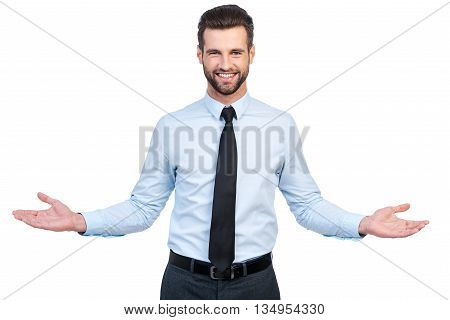 You are always welcome! Confident young handsome man in shirt and tie stretching out hands and smiling while standing against white background