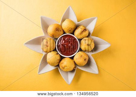 batata vada or aalu bonda or aalu bonde, a tasty indian snacks, served with tomato ketchup or green chilli and onion