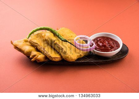 Bread Pakora or bread pakoda served along with tomato ketchup green chilly and onion slices, indian snack
