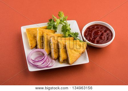 Bread Pakora or bread pakoda served along with tomato ketchup green chilly and onion slices, indian snack