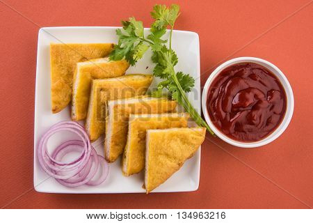 Bread Pakora or bread pakoda served along with tomato ketchup green chilly and onion slices, indian snack