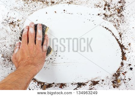 Hand with wet black sponge wiping a heavily dirty surface