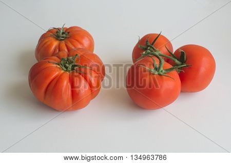 Juicy ripe beefsteak tomatoes and truss tomatoes side by side isolated on white background