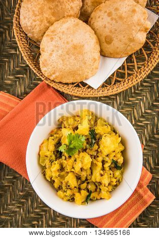 indian semi dry potato spicy recipe also known as aalu bhaji or aalu sabji served with indian puri or poori