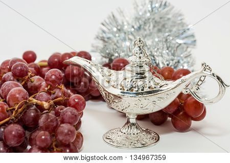 Silver Aladdin's magic lamp and red grapes. Ramadan Eid concept background
