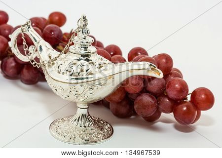 Silver Aladdin's magic lamp and red grapes. Ramadan Eid concept background