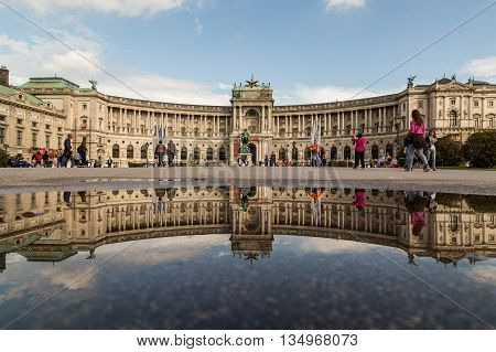 VIENNA AUSTRIA - 12TH JUNE 2016: The outside of the Austrian National Library during the day. The building can be seen reflected in a puddle. People can be seen.