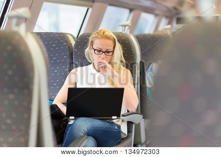 Businesswoman sitting and traveling by train working on laptop. Business travel concept.