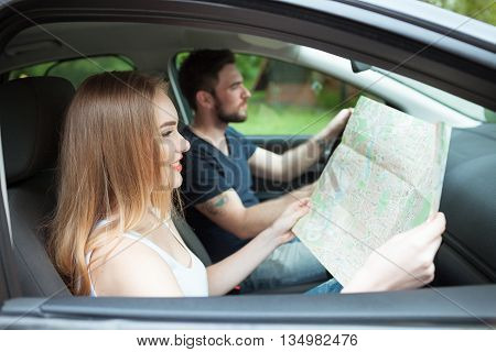 Couple of young people traveling. Couple spending weekend on nature. Searching road to go. Traveking by a car