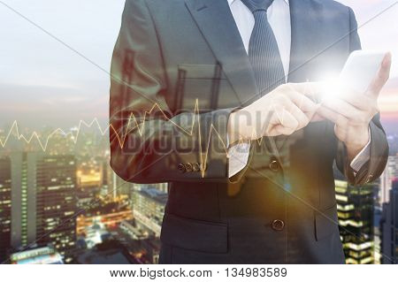Double exposure of professional businessman using smart phone blurred city centre of business and blurred tranportation port with trading graph chart Technology & Business trading concept