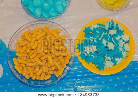 Top View Of Bowls With Colorful Sweet Tasty Gummy Candy And Bamba Snack At Children Birthday Party
