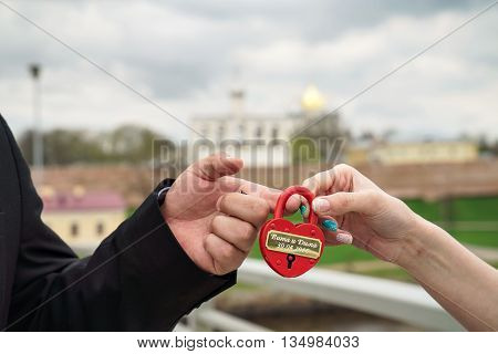 Red wedding lock with the words of Vita and Dima 30.04.2016 in the hands of the bride and groom. Wedding theme, symbol of love, newlyweds