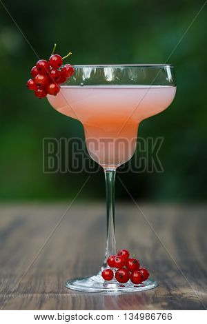 Glass of cold pink cocktail on green background bokeh