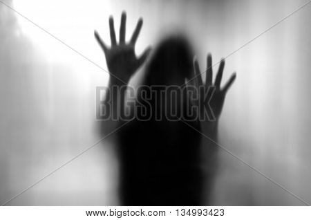 Horror woman behind the matte glass in black and white. Blurry hand and body figure abstraction.