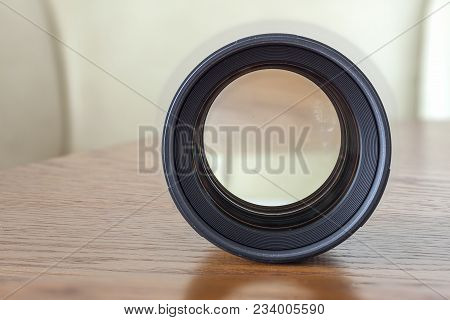 Fix Lens Of A Slr Camera Close-up With A Reflection On A Wooden Background.