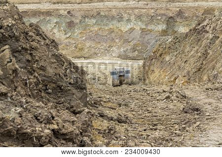 Old Dredger Bucket Between Earth Piles On Loamy Ground