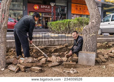 Beijing, China - April 26, 2010: Two Men In Drak Clothes Repair The Pavement Of Sidewalk At Park Alo