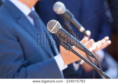 Microphone In The Focus Against Blurred Speaker. News Conference. Public Relations - Pr.