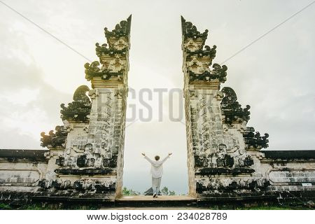 A Woman In Light Clothes With Her Arms Raised Up Symbolizes Freedom. Ancient Gates In Pura Lempuyang