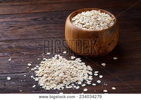 Oat Flakes In Bowl And Wooden Spoon Isolated On Dark Wooden Background, Close-up, Selective Focus, S