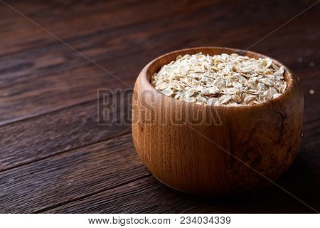 Oat Flakes In Bowl And Wooden Spoon Isolated On Dark Wooden Background, Close-up, Selective Focus, S