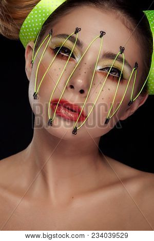 Woman In Conceptual Make Up With Neon Thread On Face On Black Background In Studio Photo. Extreme Be