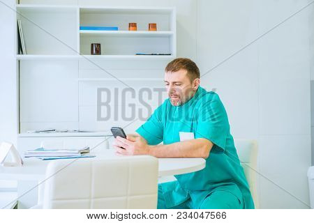 Doctor Using Mobile Smart Phone, Sitting In Medical Room In The Hospital, Electronic Health Records 