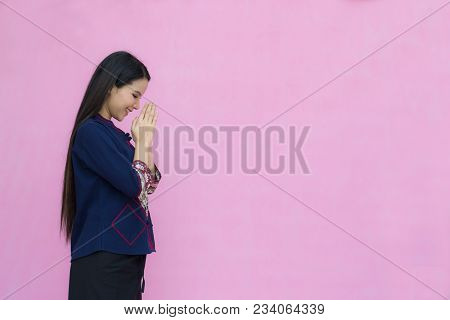 Portrait Of Asian Youn Girl In Traditional Thai Dress Praying Isolated On Pink Background. Wai Sawat